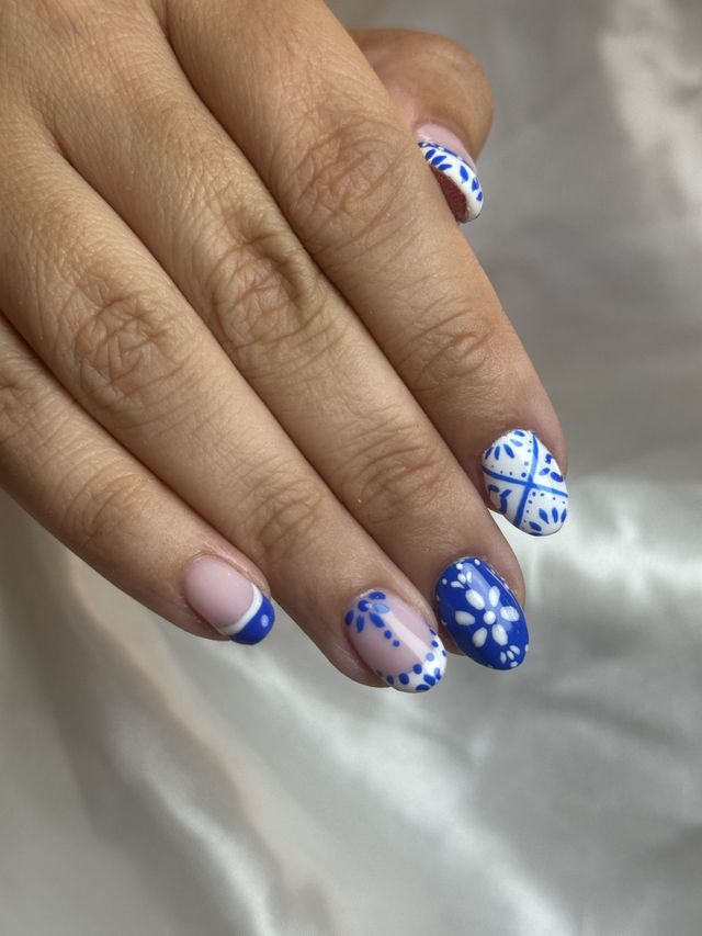 Nail art con motivos azules y blancos estilo talavera